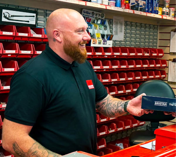 Trade counter assistant handing a Bristan product box to a customer in a merchant showroom