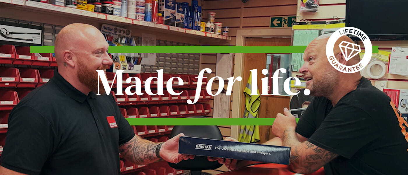 Bristan product being handed to a customer at a merchant trade counter, with Bristan Lifetime Guarantee branding